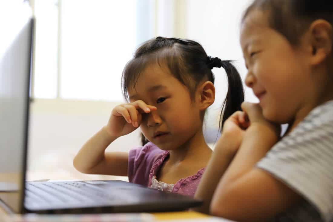 two asian girls feel tired in online class at home because of covid-19.