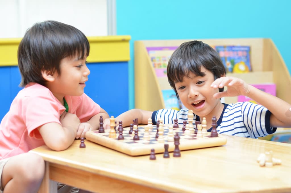 Little siblibg boy playing chess