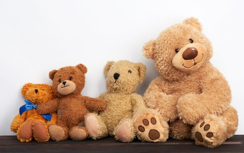 various-brown-teddy-bears-are-sitting-on-a-brown-wooden-table-picture-id1225449650