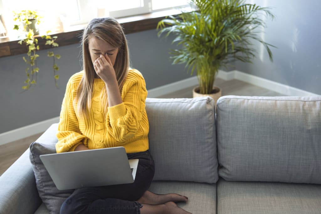 Shot of a young woman looking stressed while using a laptop to work from home. Exhausted girl massage eyes suffering from blurry vision. All this is causing me headache!