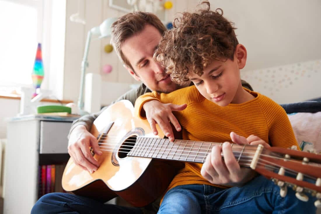 Играет на гитаре в школе. Гитарист учит сына. Отец учит сына играть на гитаре. Папа дома. Папа играет на гитаре