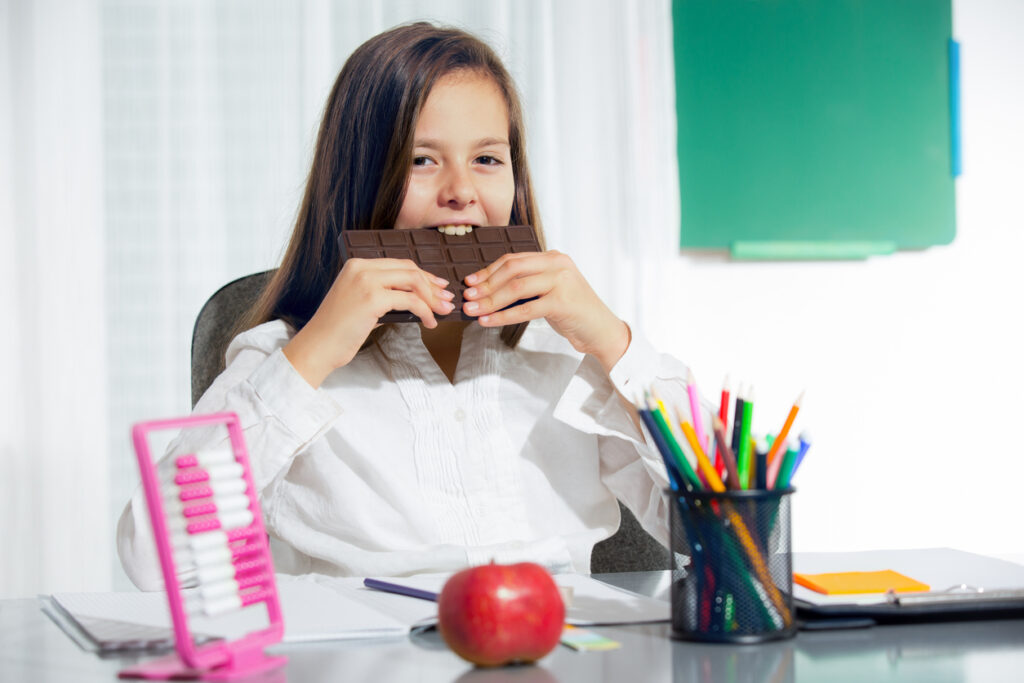 Little girl eat chocolate at room