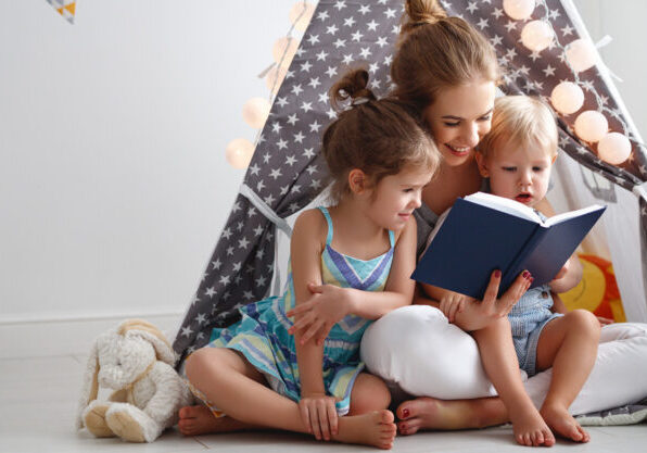 family mother reading to children book in tent in playroom at home