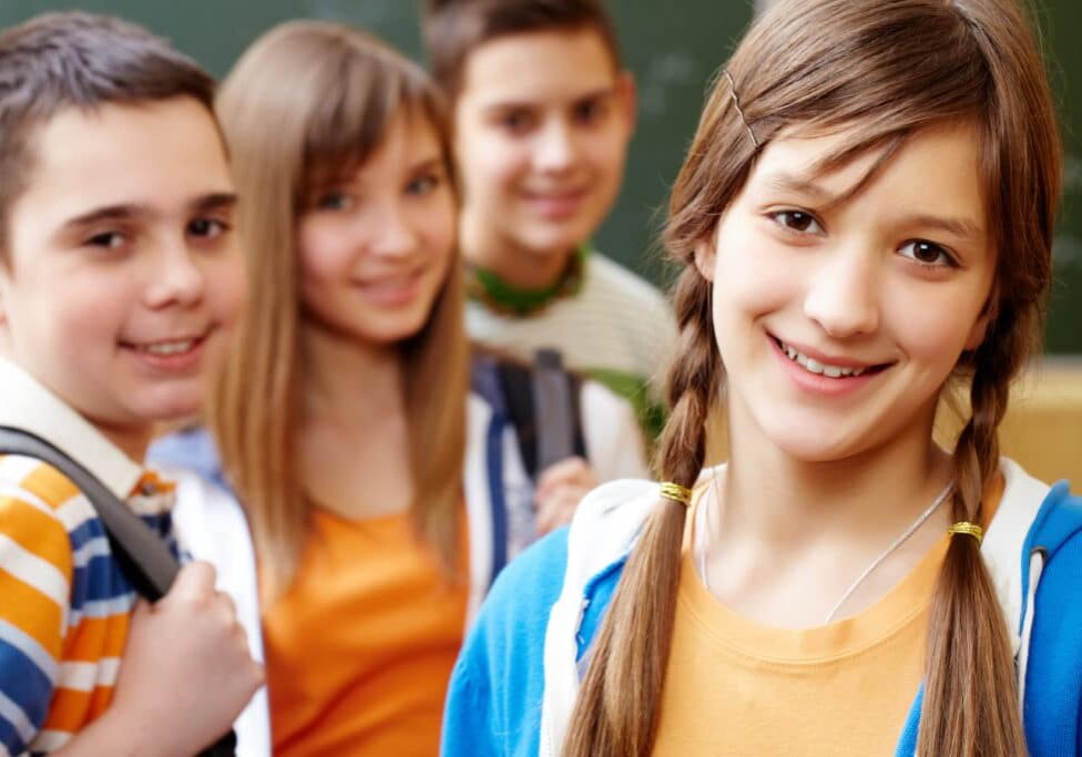 Confident student looking at camera with her friends behind