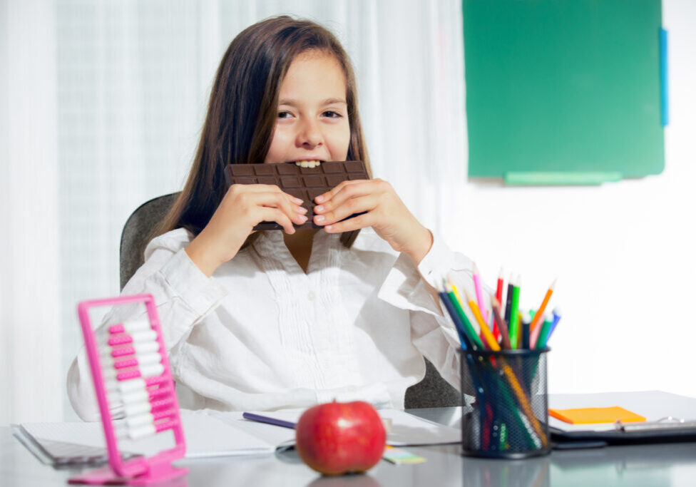 Little girl eat chocolate at room